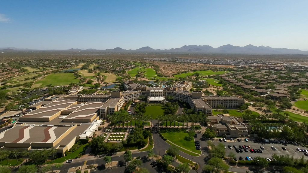 Aerial view of a large resort surrounded by golf courses and residential areas, with mountains in the background.